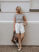 a lady wears a striped off shoulder top with white bermuda shorts